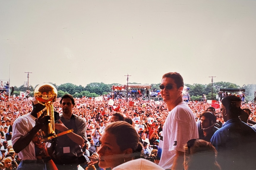 View from the stage looking over a large crowd of Chicago Bulls fan. Luc Longley looks back at camera