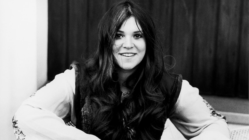 A black and white picture of a young Melanie taken in 1974, smiling, long hair, vest