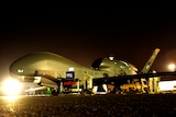 A Global Hawk spy drone is prepared for a night mission at an undisclosed location in the Middle East.