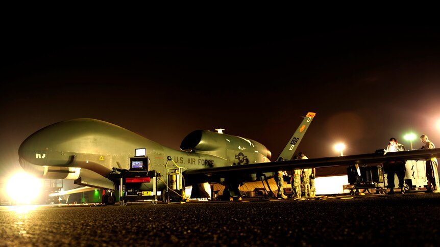 A Global Hawk spy drone is prepared for a night mission at an undisclosed location in the Middle East.
