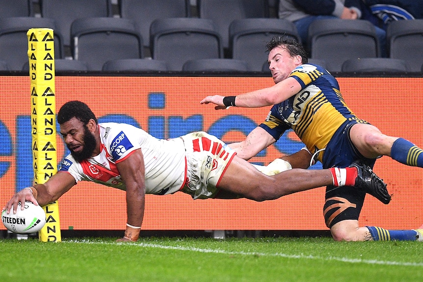 Mikaele Ravalawa dives full length next to the corner flag to ground the ball as an opposition player tackles him from behind