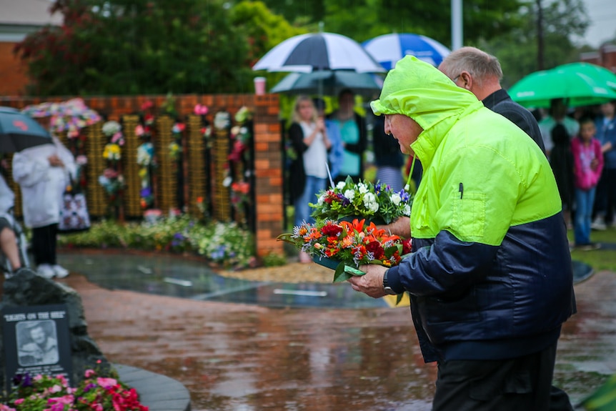 A truckie lays a wreath against a memorial wall.