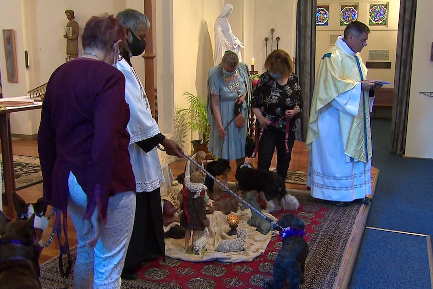People stand around an altar with their pets.
