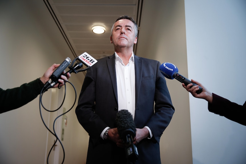 Darren Chester in a suit standing in front of microphones during a press conference