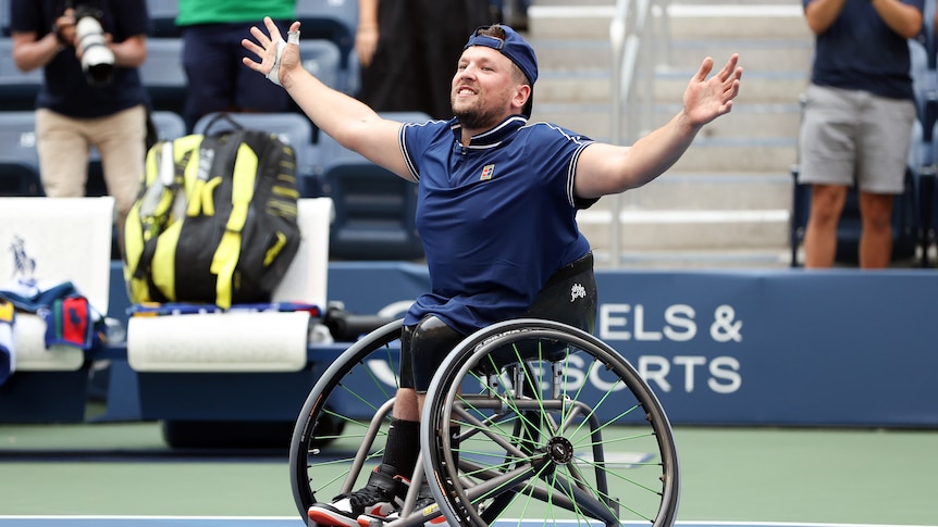 A smiling Dylan Alcott holds his arms out wide on court after the final point of his US Open quad singles final.