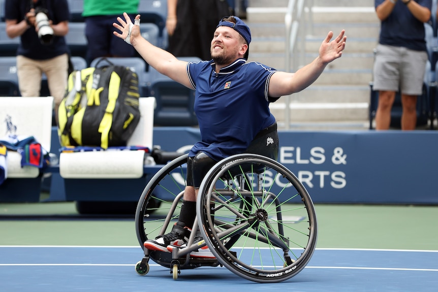 A smiling Dylan Alcott holds his arms out wide on court after the final point of his US Open quad singles final.