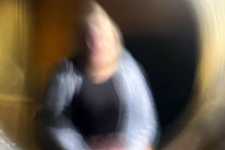 Une photo floue d'une femme blonde dans un cardigan