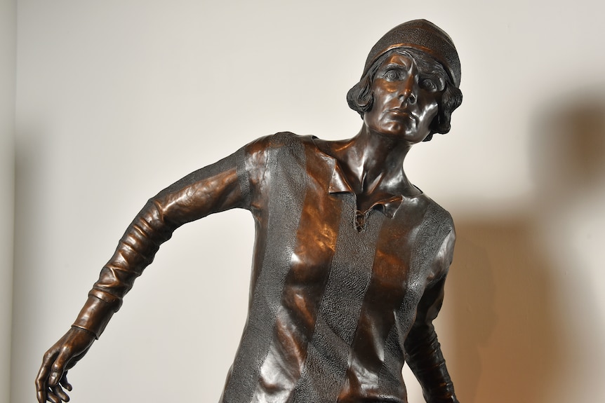 A bronze statue of a woman wearing a striped shirt and cap