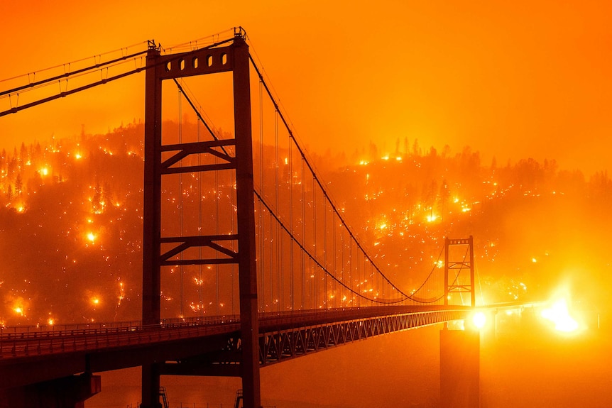 Embers light up a hillside as it glows bright orange behind the Bidwell Bar Bridge.