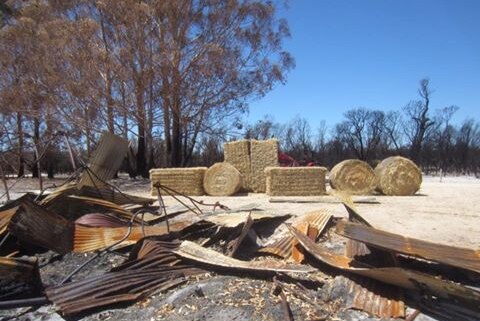 Bales of hay next to a burnt out shed.