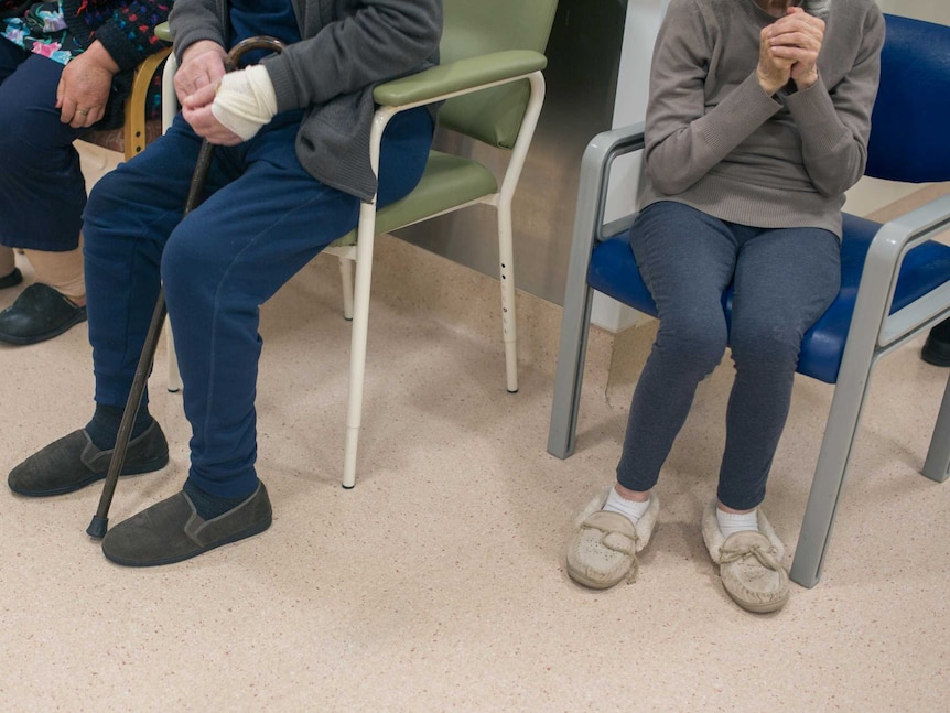 Patients in the ward sit near the nurse's station.