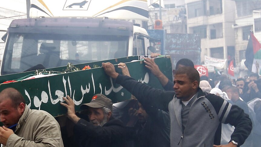 Palestinian mourners run through tear gas with the coffin of a teenage boy