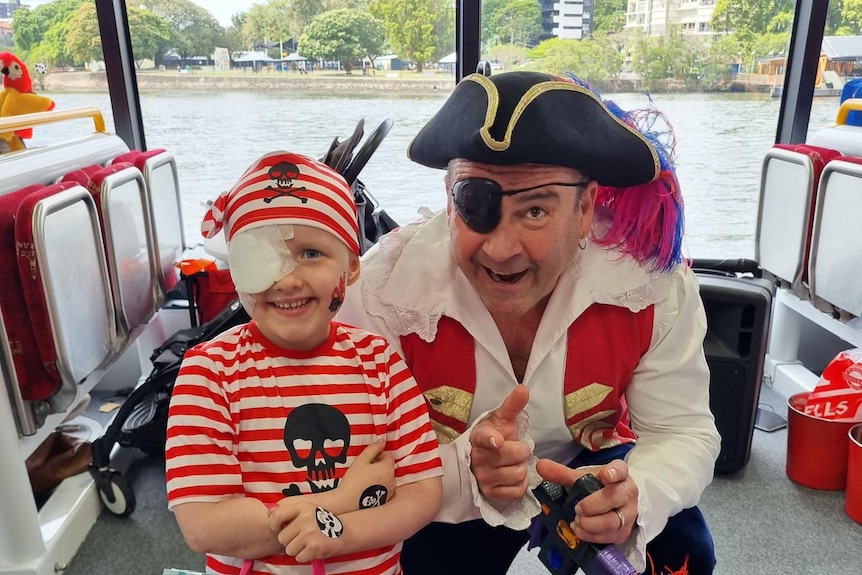 A smiling child with a party bag and a man in a pirate costume