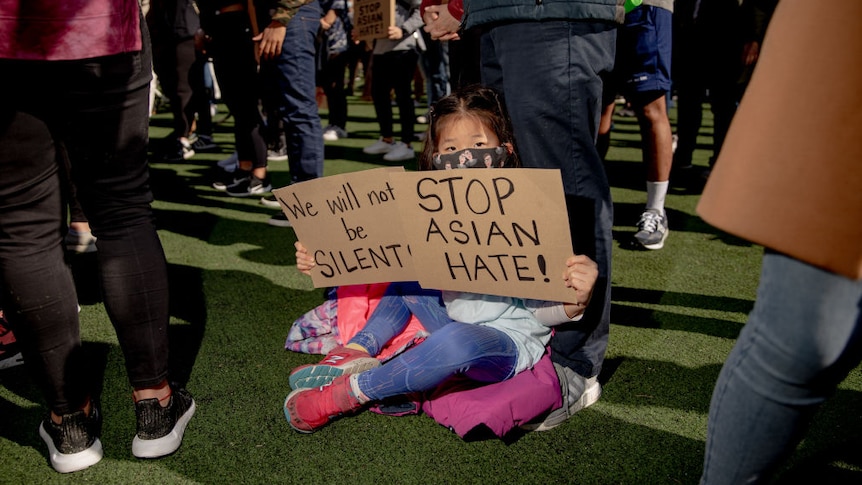 A child holds a signs during an rally against Asian hate crimes