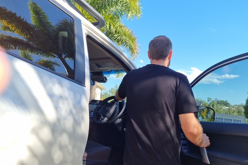 the back of a man as he is about to get into a four wheel drive