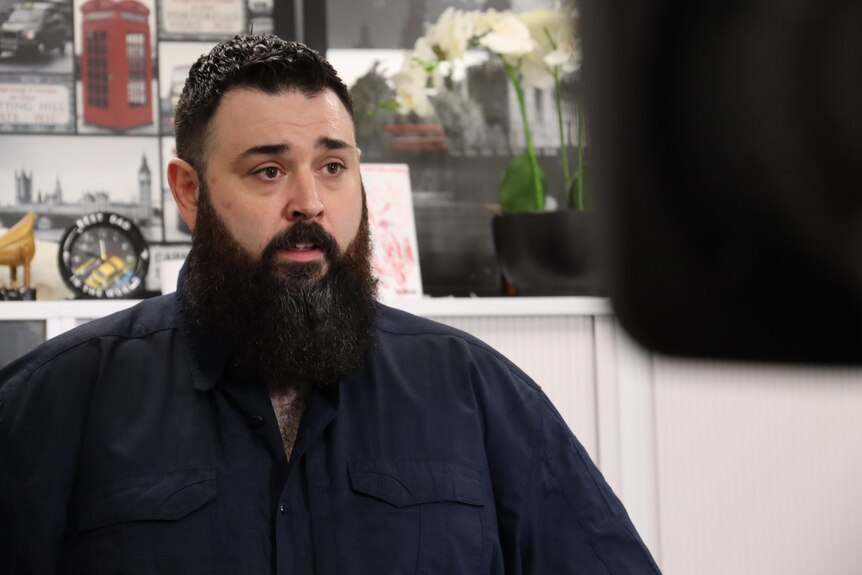 Man with beard talks to a journalist behind a camera