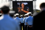 Uniform police officers in front of a screen showing Senior Constable Dave Masters at his funeral