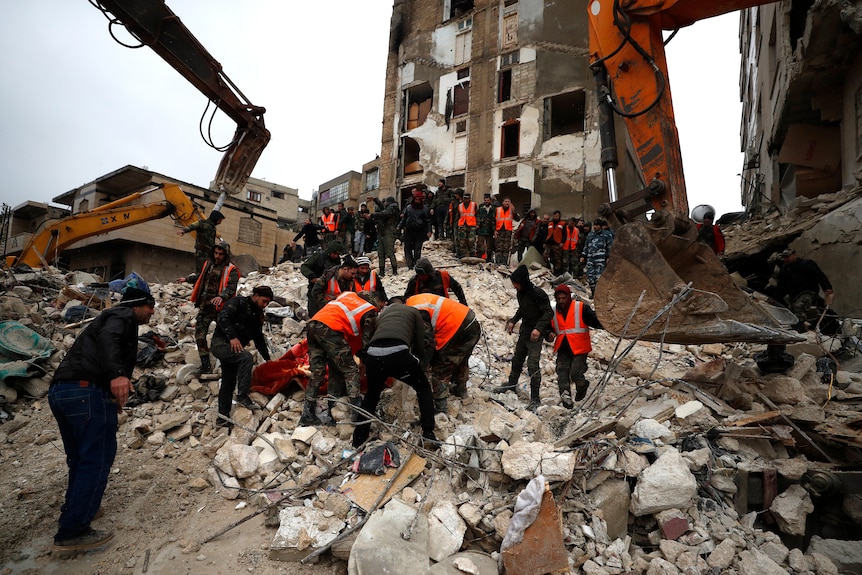 Civil defense workers and security forces search through the wreckage of collapsed buildings.