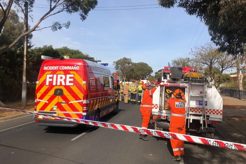 SES rescue workers and fire crew standing on a road next to vehicles in front of a house
