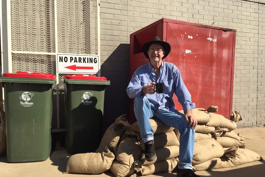 A man sitting on sandbags with a cup of tea