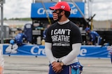 A NASCAR driver stands at a track in a shirt saying "I can't breathe, Black Lives Matter".