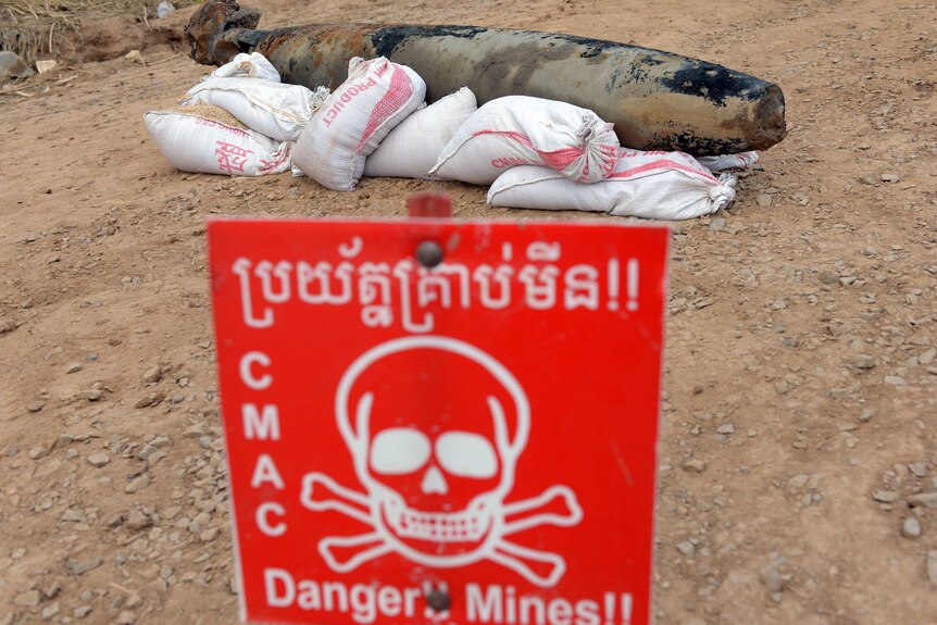 A Mark 82 bomb is seen behind a warning sign after being pulled from the Mekong river in Kandal province