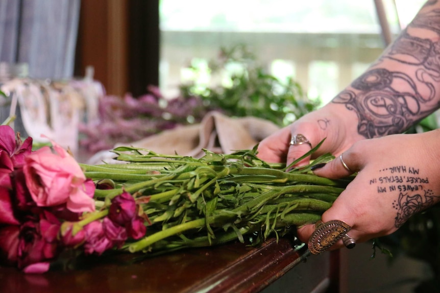 A woman's hands working on a flower arrangement.