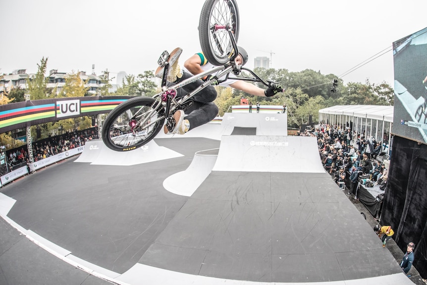 A woman pulls a trick on an airborne bicycle