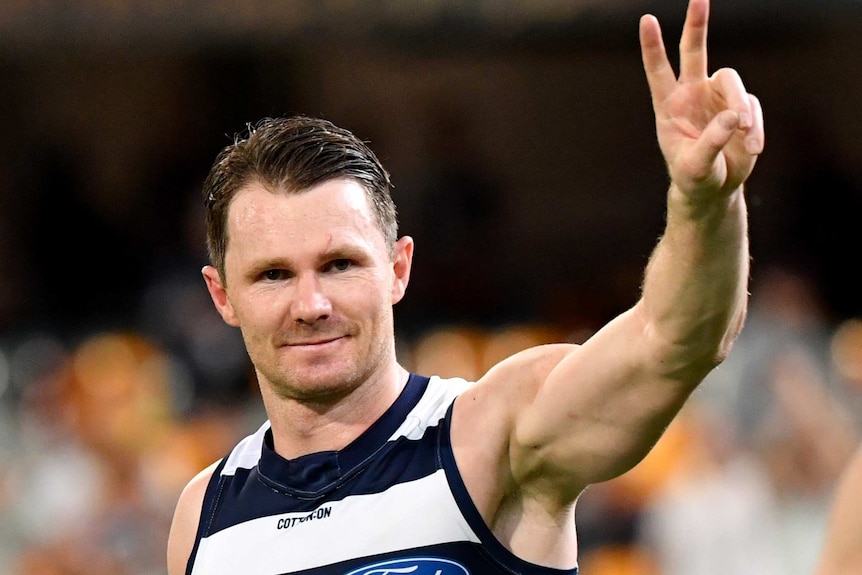 Patrick Dangerfield smiles and gives the peace sign to the crowd