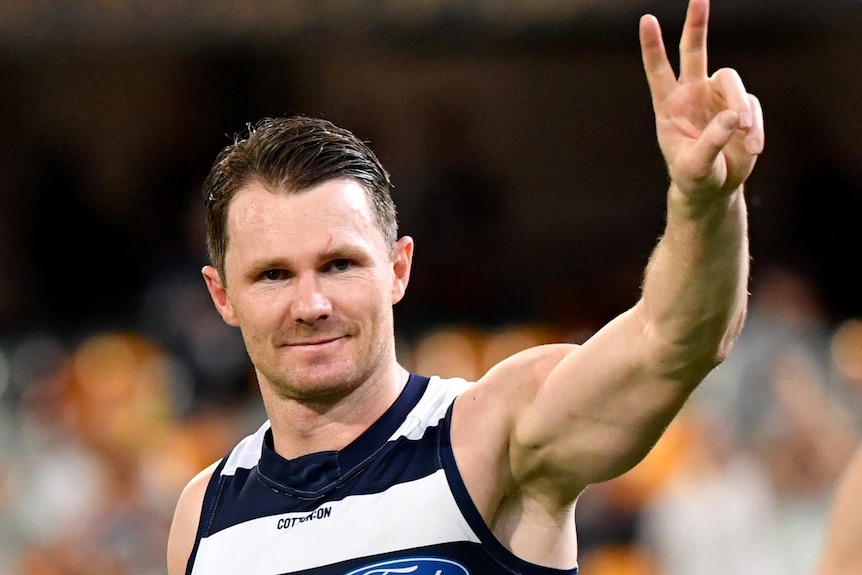 Patrick Dangerfield smiles and gives the peace sign towards the crowd