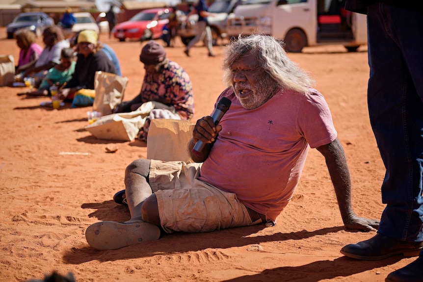 George Tjungurrayi in Kintore hold a microphone.