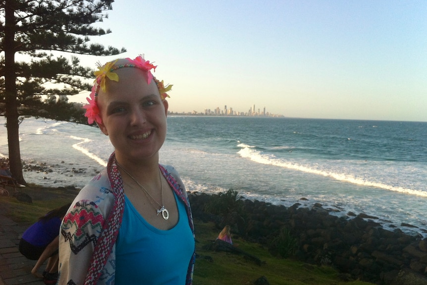 Kathryn at the beach, wearing a flower crown and blue single top with colorful jacket.