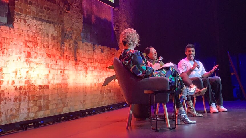 Zan Rowe, Myf Warhurst and Nazeem Hussain seated onstage under a large poster saying "Bang On"