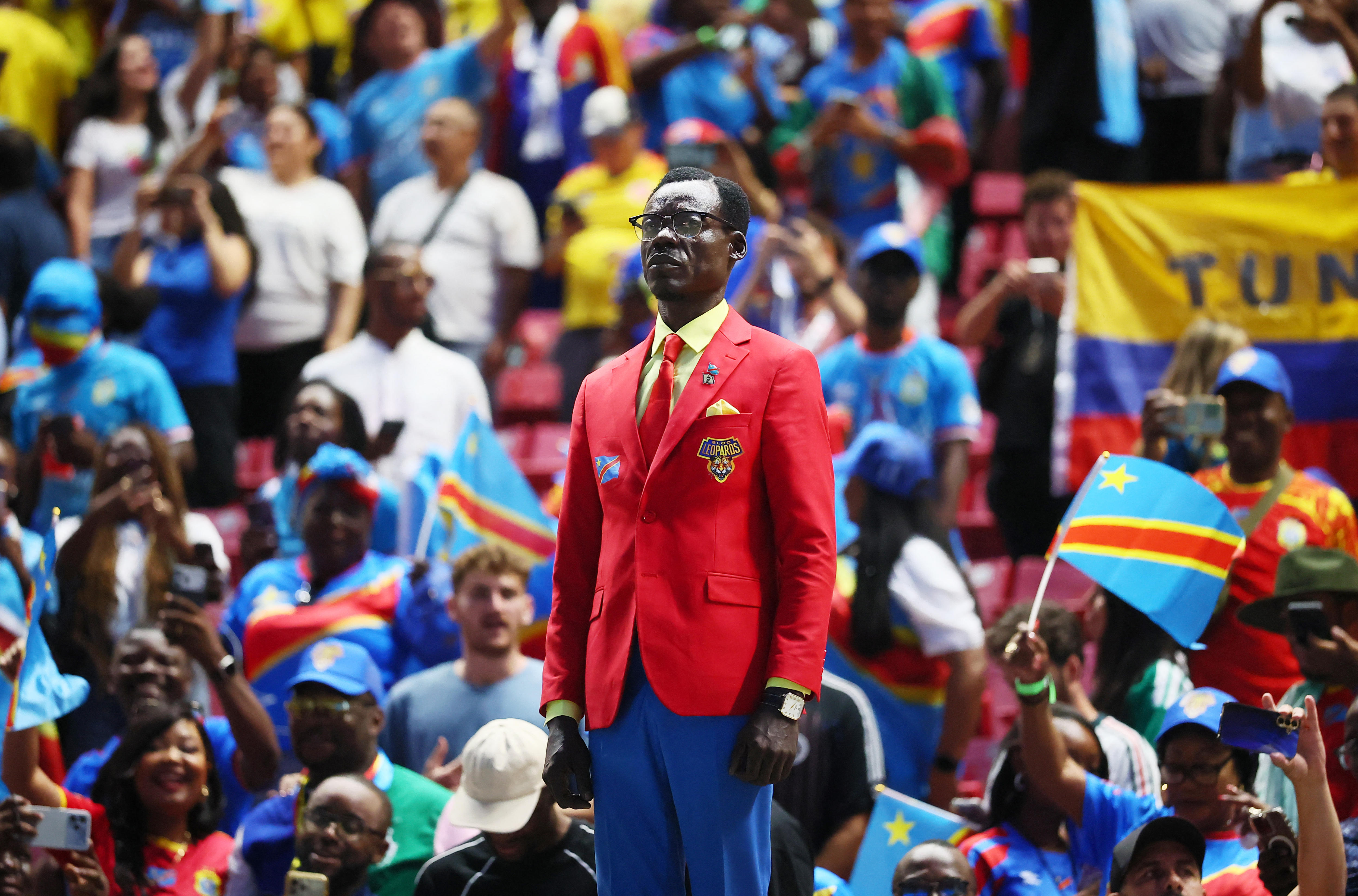 Michel Nkuka Mboladinga standing still amongst the cheering crowd