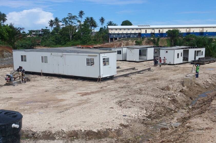 Ongoing work at one of the new refugee accommodation sites on Manus Island. There are portables on a large cleared dirt site.