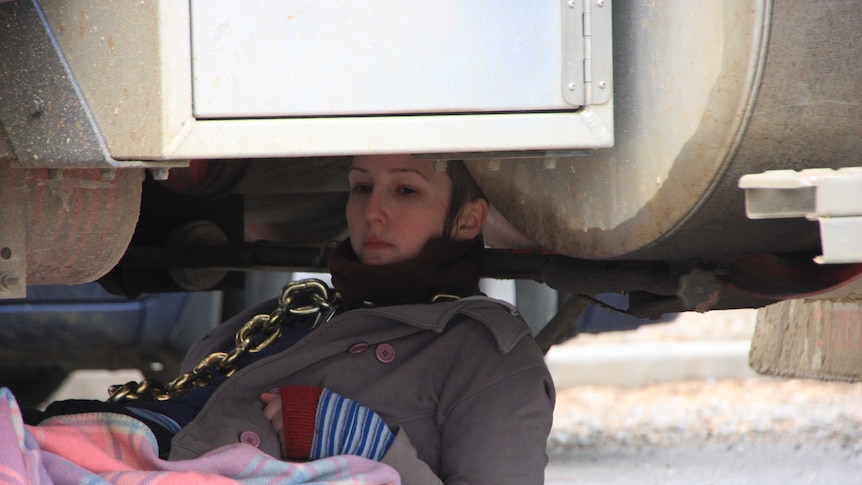 An anti-logging protester lies chained underneath a log truck at Bell Bay, northern Tasmania