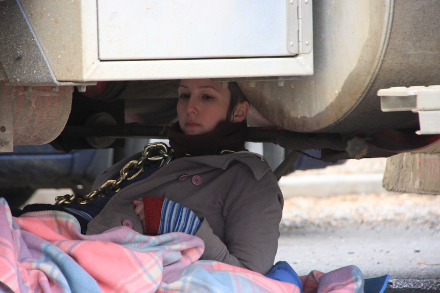 An anti-logging protester lies chained underneath a log truck at Bell Bay, northern Tasmania