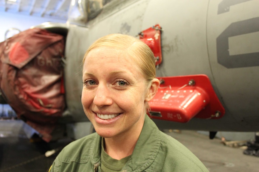 US Marine Corps Captain Kelsey Casey standing in front of a AV-8B Harrier aircraft.