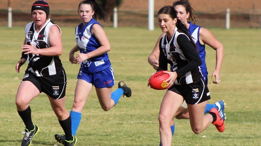 Women run down a field during a football game in country Victoria.