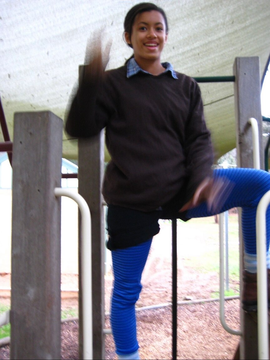 Yasmin wears thermal leggings under shorts, a jumper and a collared shirt and waves on a playground