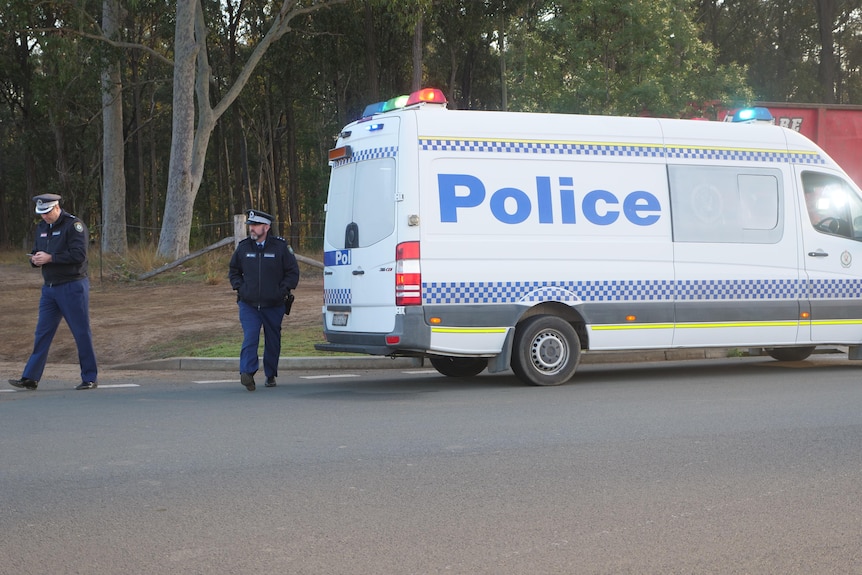 Police officers next to a police van.