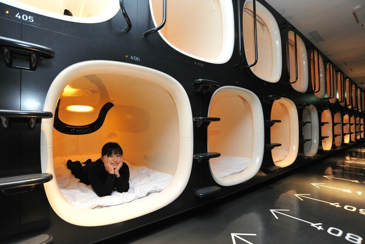 A woman lies in a capsule at a capsule hotel.