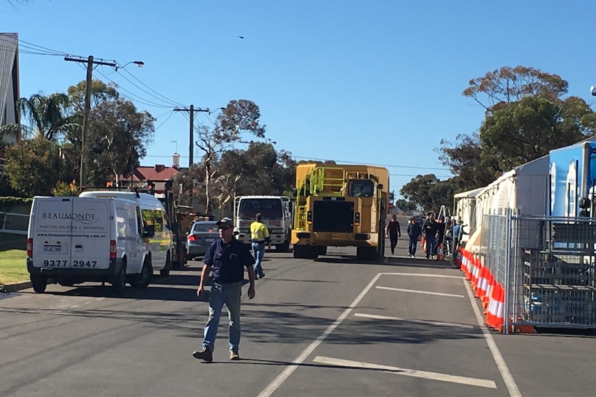 A large truck moves down a suburban street in Kalgoorlie-Boulder, guided into place by workers.