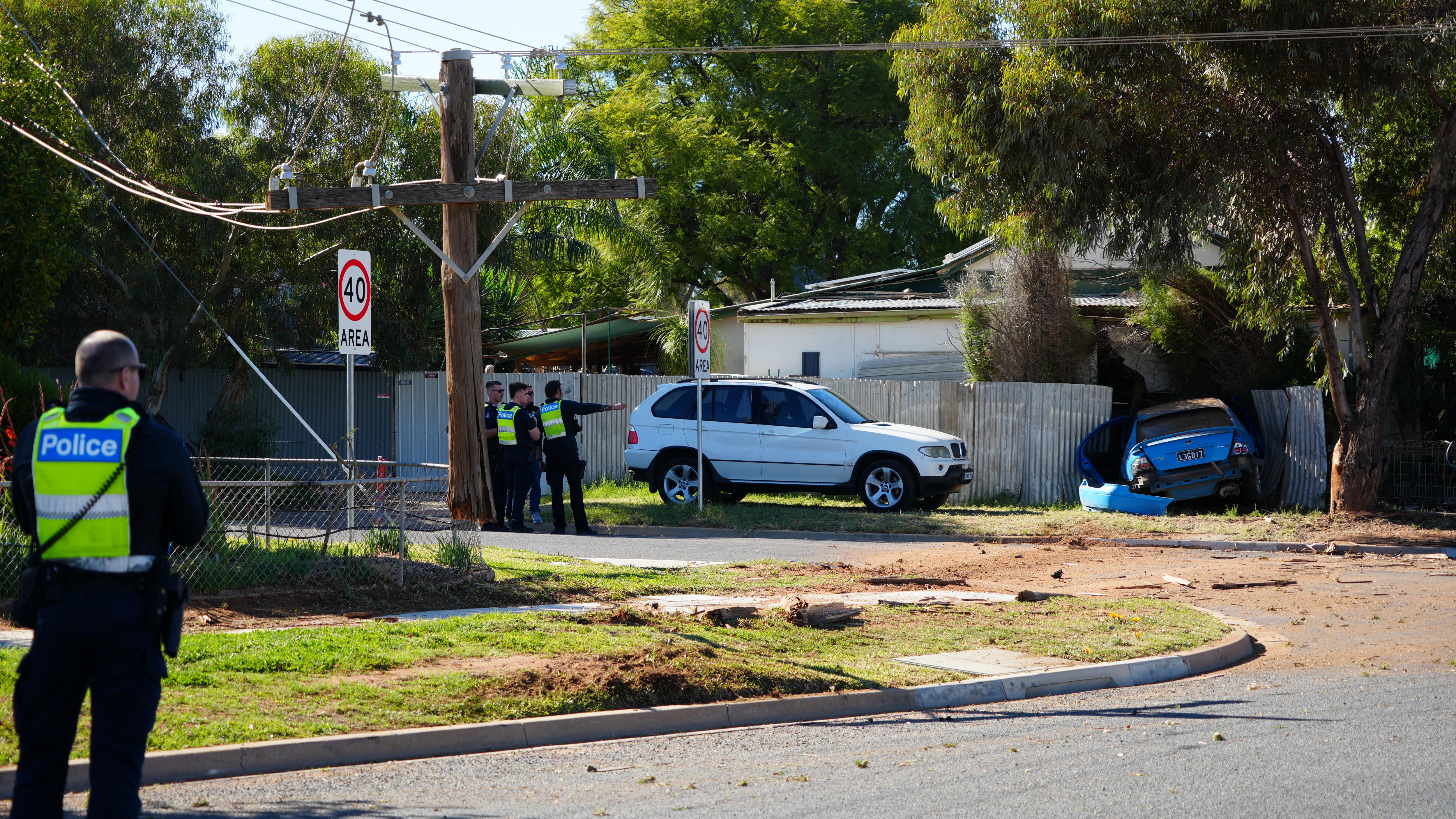 The scene of a car crash, where a car has hit a power pole and a home