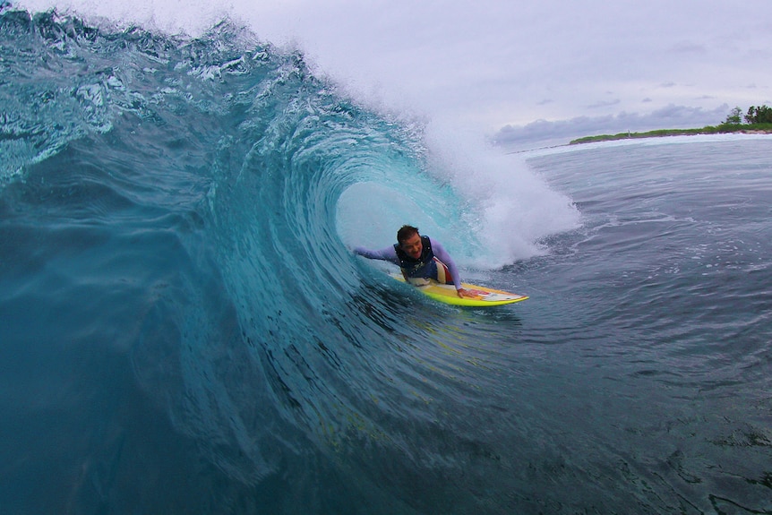 A man rides through the tube of a wave on his surfboard
