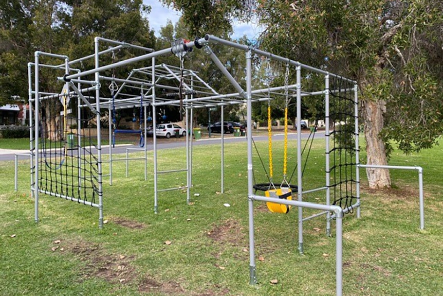 Metal play equipment on a grassed verge in a residential street.