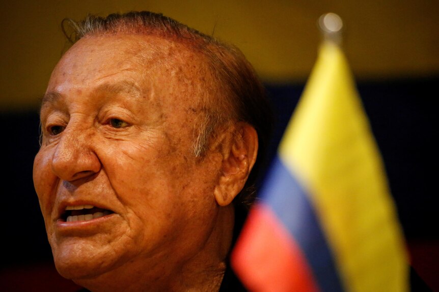 Rodolfo Hernandez speaking in front of a Colombian flag 