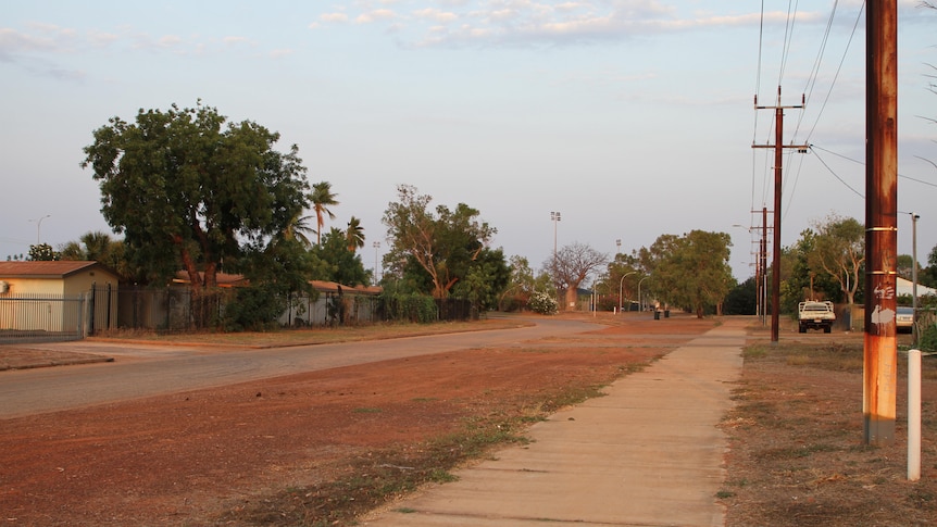 The main strip of Derby, a narrow road surrounded by red dirt and bushy trees.