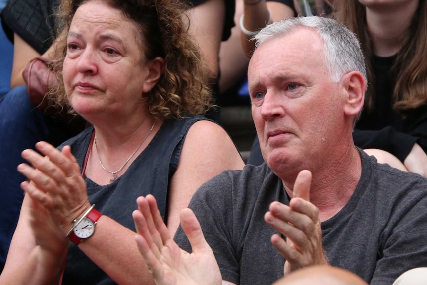 A woman and a man applaud with tears in their eyes at the vigil for Aiia Maasarwe.