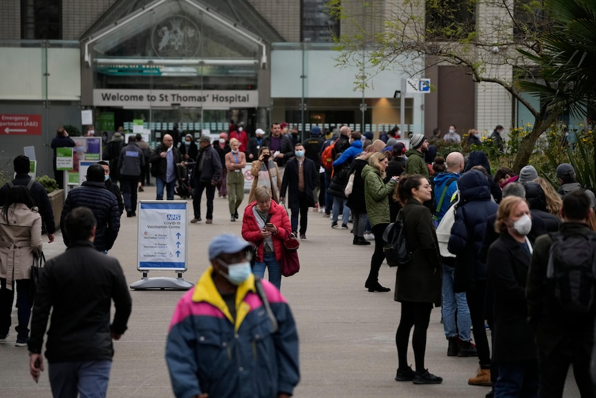 People queue in a line to go for coronavirus booster jabs